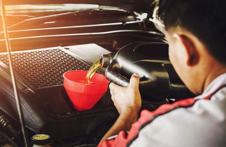 Technician pouring fresh oil into a funnel